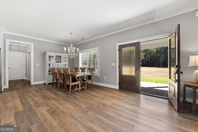 dining space featuring baseboards, an inviting chandelier, wood finished floors, and ornamental molding