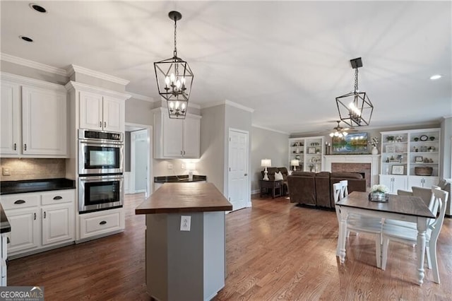 kitchen with butcher block countertops, open floor plan, a fireplace, stainless steel double oven, and dark wood-style flooring