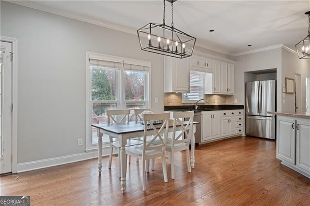 dining area with crown molding, a notable chandelier, wood finished floors, and baseboards