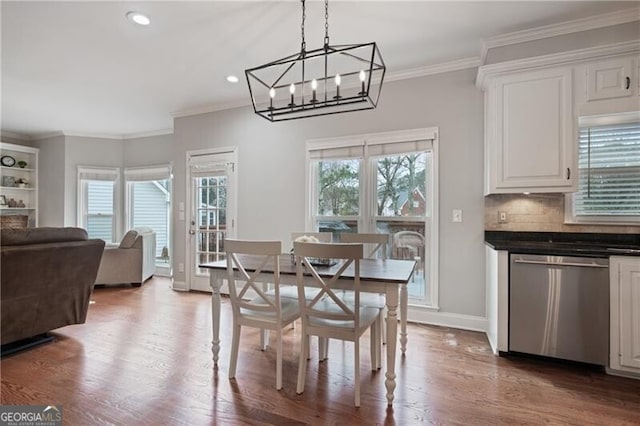 dining room featuring baseboards, wood finished floors, a healthy amount of sunlight, and ornamental molding