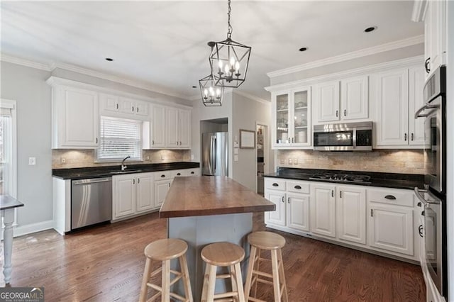 kitchen with wood counters, white cabinets, appliances with stainless steel finishes, and a sink