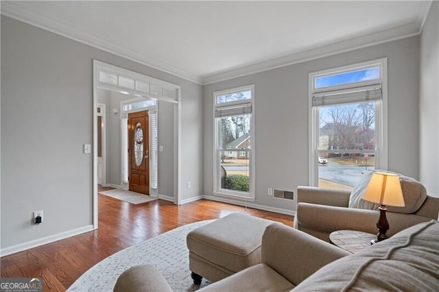 living room featuring visible vents, baseboards, wood finished floors, and crown molding