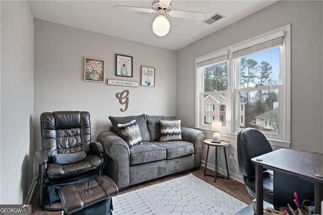 living area featuring a ceiling fan, wood finished floors, visible vents, and baseboards