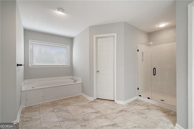 bathroom featuring a bath, a shower stall, marble finish floor, and baseboards