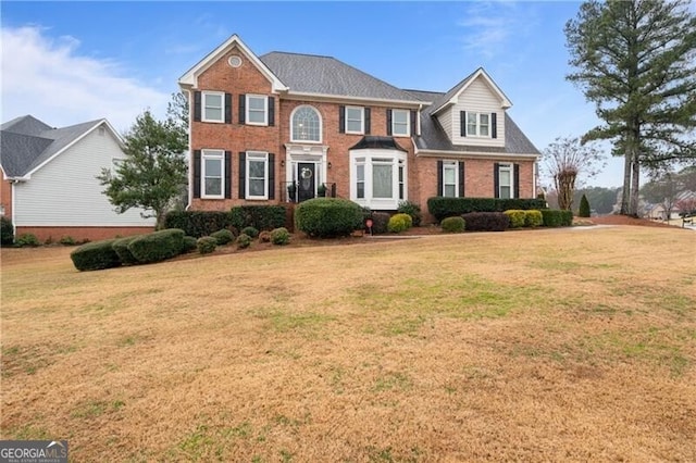 colonial inspired home with brick siding and a front yard