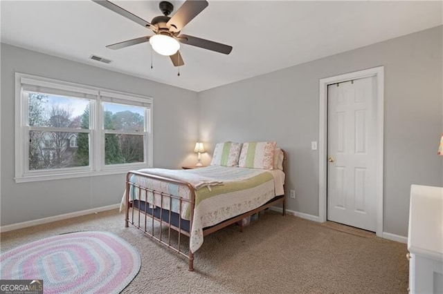 bedroom featuring visible vents, light colored carpet, baseboards, and ceiling fan