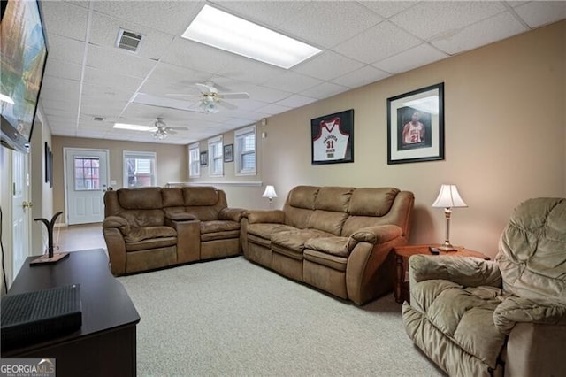 carpeted living area featuring a drop ceiling, visible vents, and ceiling fan