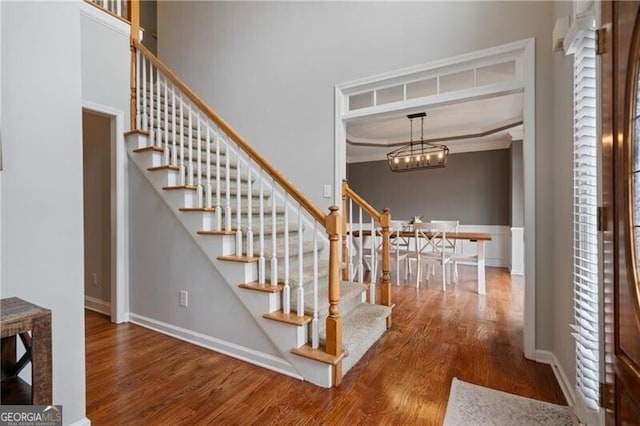 stairs with a notable chandelier, baseboards, and wood finished floors