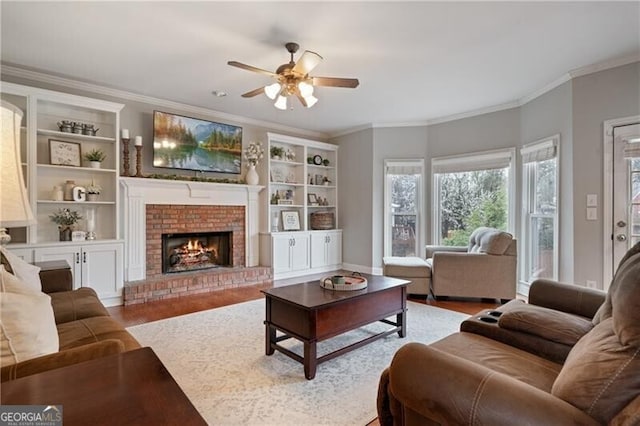 living room featuring ceiling fan, wood finished floors, a fireplace, and crown molding