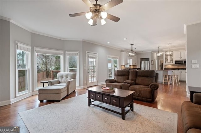 living area featuring plenty of natural light, ornamental molding, baseboards, and wood finished floors