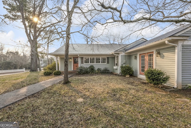 ranch-style home featuring a front lawn and metal roof