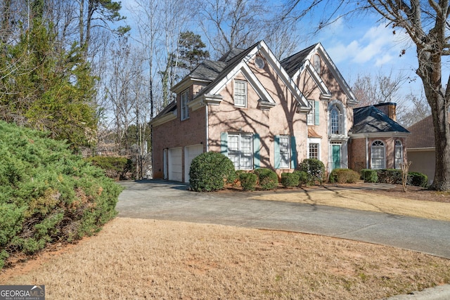 traditional-style house with brick siding, driveway, and an attached garage