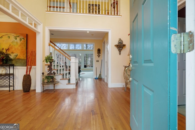 foyer entrance featuring stairs, crown molding, a high ceiling, and wood finished floors