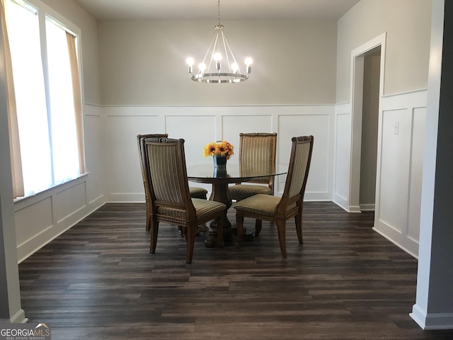 dining area with an inviting chandelier, dark wood-style floors, wainscoting, and a decorative wall