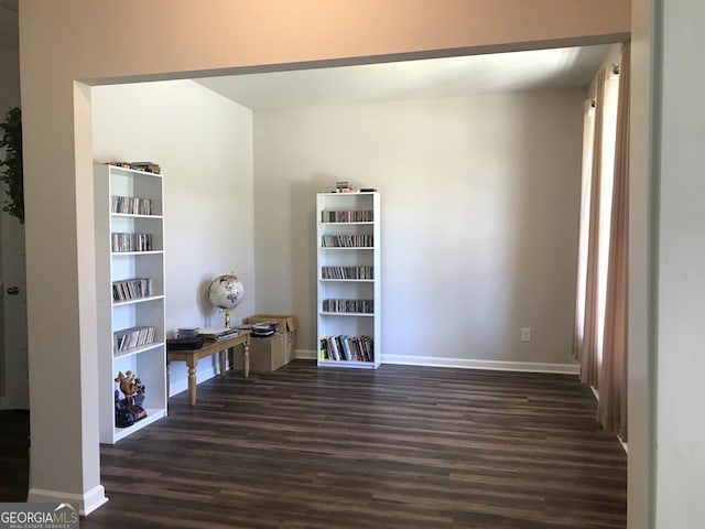 unfurnished room with dark wood-type flooring and baseboards