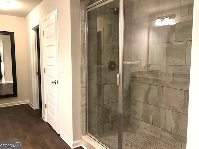 bathroom with baseboards, wood finished floors, and a shower stall