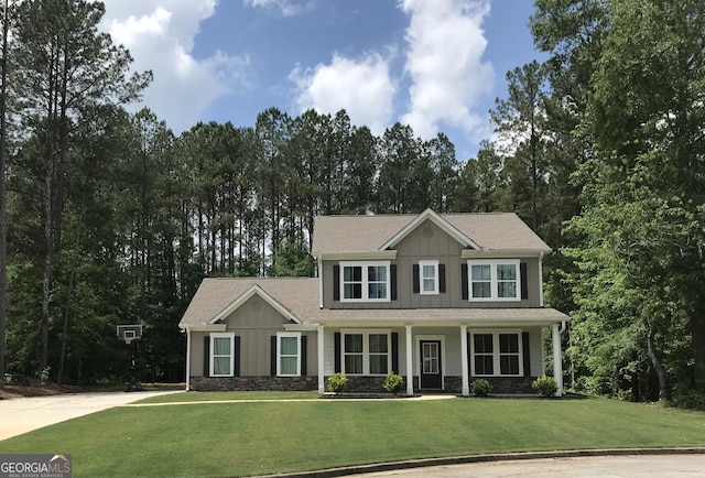 view of front of house with board and batten siding, a front yard, stone siding, and covered porch