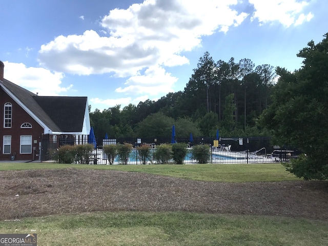 exterior space featuring a pool, a yard, and fence