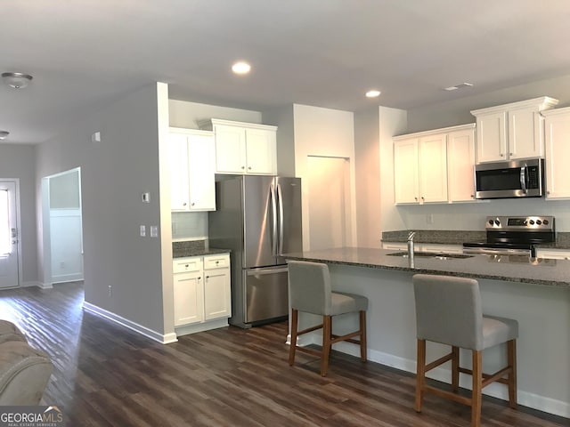 kitchen featuring dark stone countertops, a sink, recessed lighting, appliances with stainless steel finishes, and dark wood-style flooring