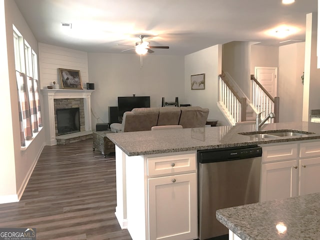 kitchen featuring a sink, dark wood-style floors, a stone fireplace, white cabinets, and dishwasher