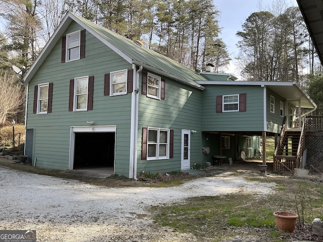 exterior space with stairs, an attached garage, a carport, and driveway