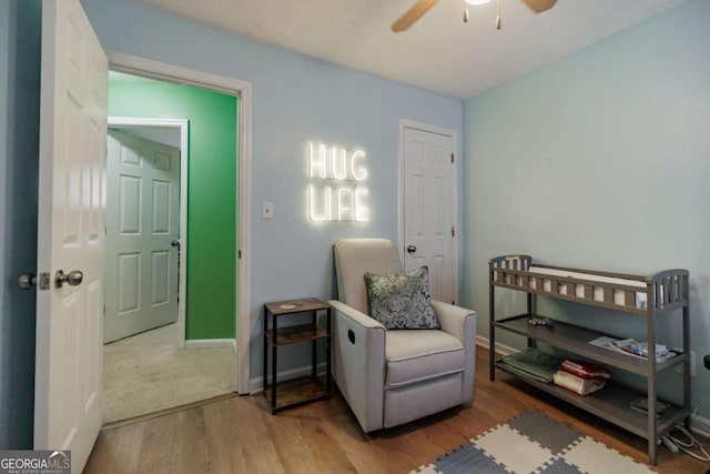 sitting room featuring a ceiling fan, wood finished floors, and baseboards