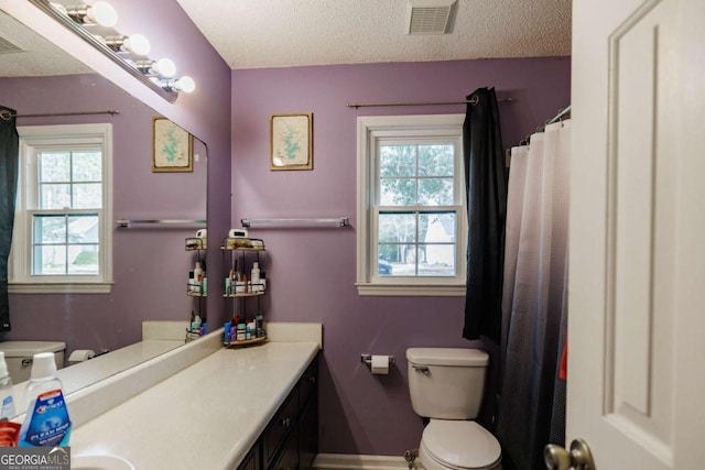 bathroom with visible vents, plenty of natural light, toilet, and vanity