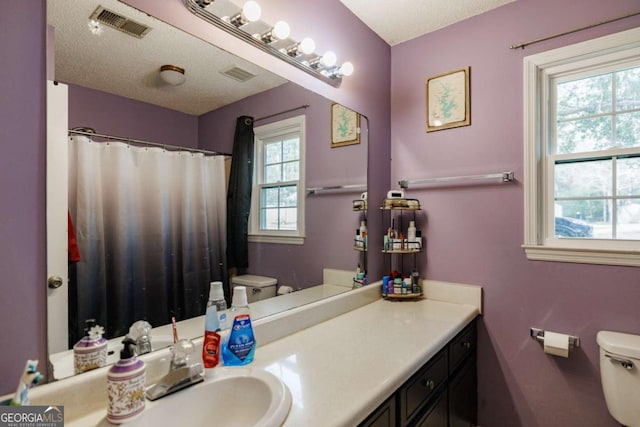 full bathroom featuring visible vents, a textured ceiling, toilet, and vanity