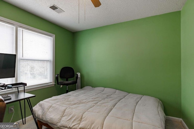 carpeted bedroom with a ceiling fan, baseboards, visible vents, and a textured ceiling