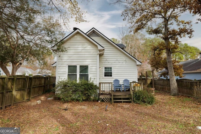 rear view of house featuring a wooden deck and a fenced backyard