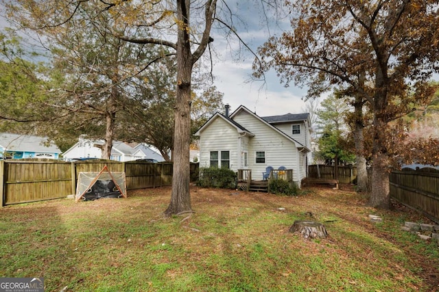 rear view of house featuring a yard and a fenced backyard