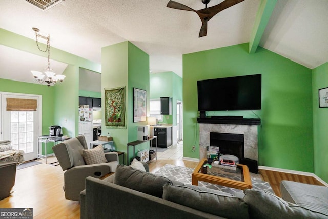 living area featuring visible vents, lofted ceiling with beams, a high end fireplace, light wood-style floors, and ceiling fan with notable chandelier