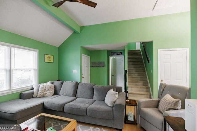 living area featuring light wood-type flooring, stairway, ceiling fan, and vaulted ceiling with beams