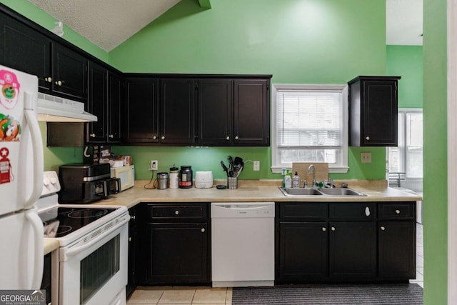 kitchen featuring under cabinet range hood, light countertops, vaulted ceiling, white appliances, and a sink