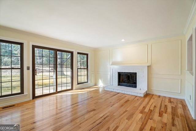 unfurnished living room featuring light wood-style floors, crown molding, and a decorative wall