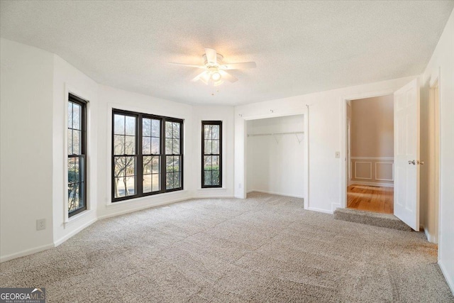 unfurnished bedroom featuring a closet, a textured ceiling, ceiling fan, and carpet floors