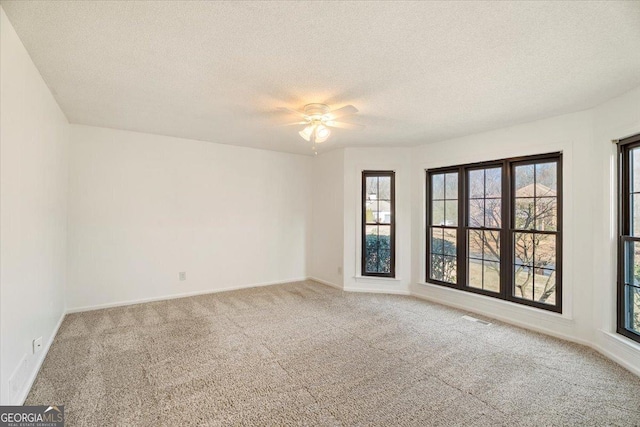 spare room featuring visible vents, baseboards, ceiling fan, carpet, and a textured ceiling