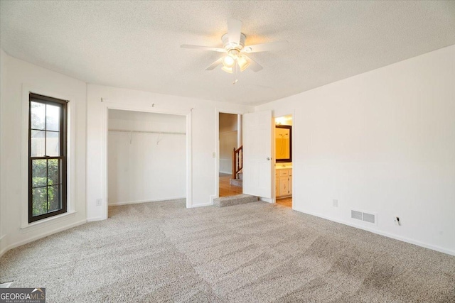 unfurnished bedroom featuring visible vents, baseboards, light carpet, a closet, and a textured ceiling