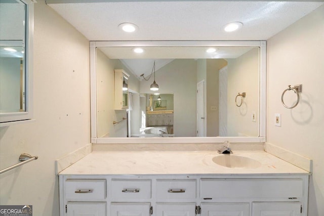 bathroom with vanity, lofted ceiling, and recessed lighting