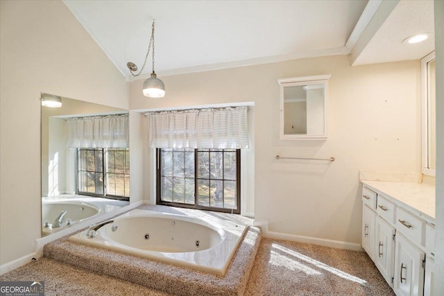 bathroom featuring vanity, baseboards, lofted ceiling, ornamental molding, and a jetted tub