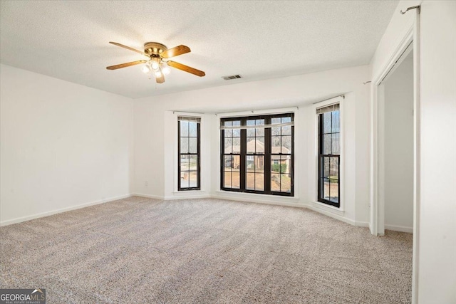 unfurnished room with visible vents, a textured ceiling, a ceiling fan, and carpet