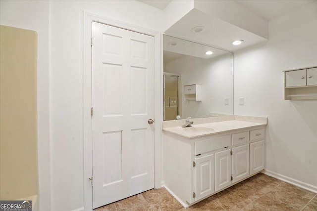 bathroom with a shower with door, recessed lighting, vanity, and baseboards