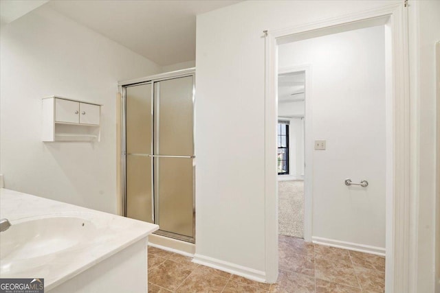 full bath featuring baseboards, vanity, and a shower stall