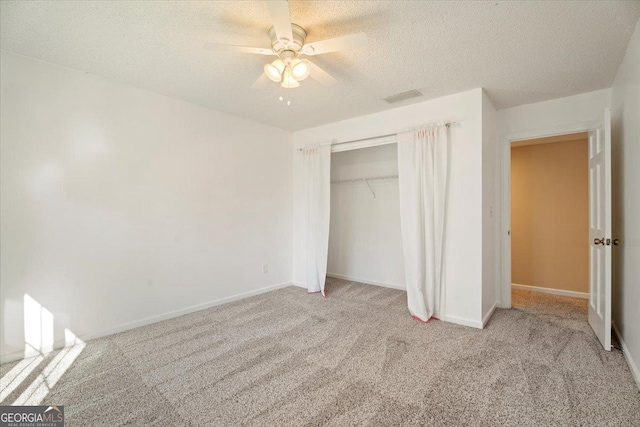 unfurnished bedroom with visible vents, a textured ceiling, a closet, carpet floors, and baseboards