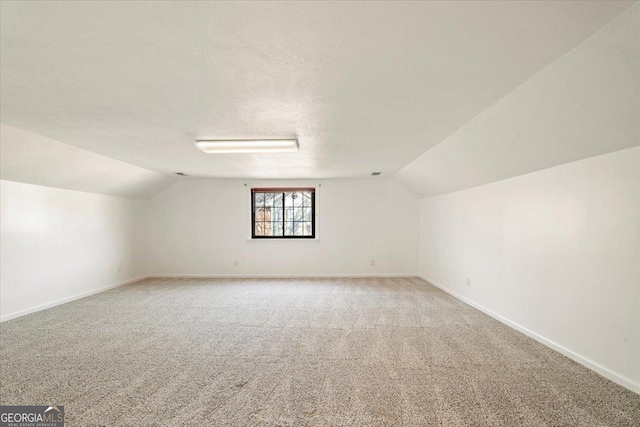 bonus room featuring lofted ceiling, baseboards, and a textured ceiling