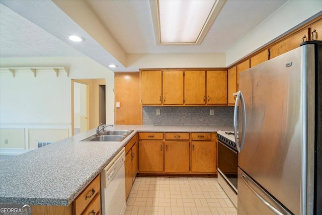 kitchen with brown cabinets, a sink, recessed lighting, white appliances, and decorative backsplash