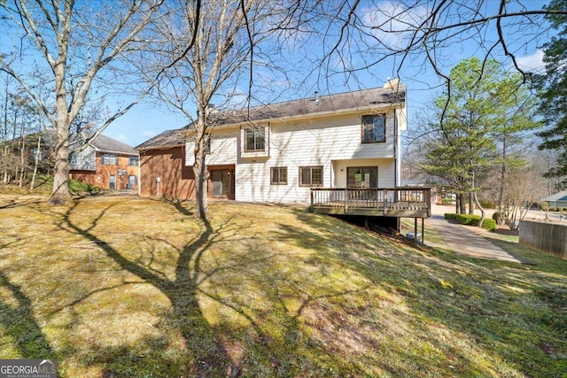 back of property with a lawn, a deck, and fence