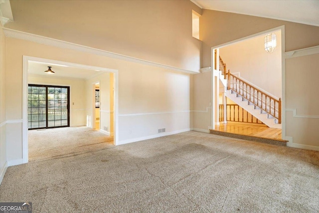 unfurnished living room featuring carpet flooring, crown molding, and stairs