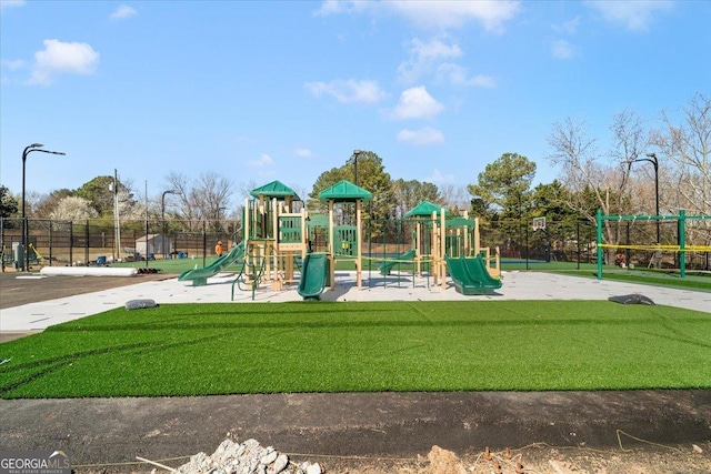 communal playground featuring a lawn and fence