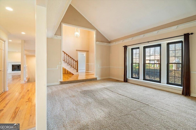 interior space featuring baseboards, lofted ceiling, a fireplace, stairs, and carpet flooring